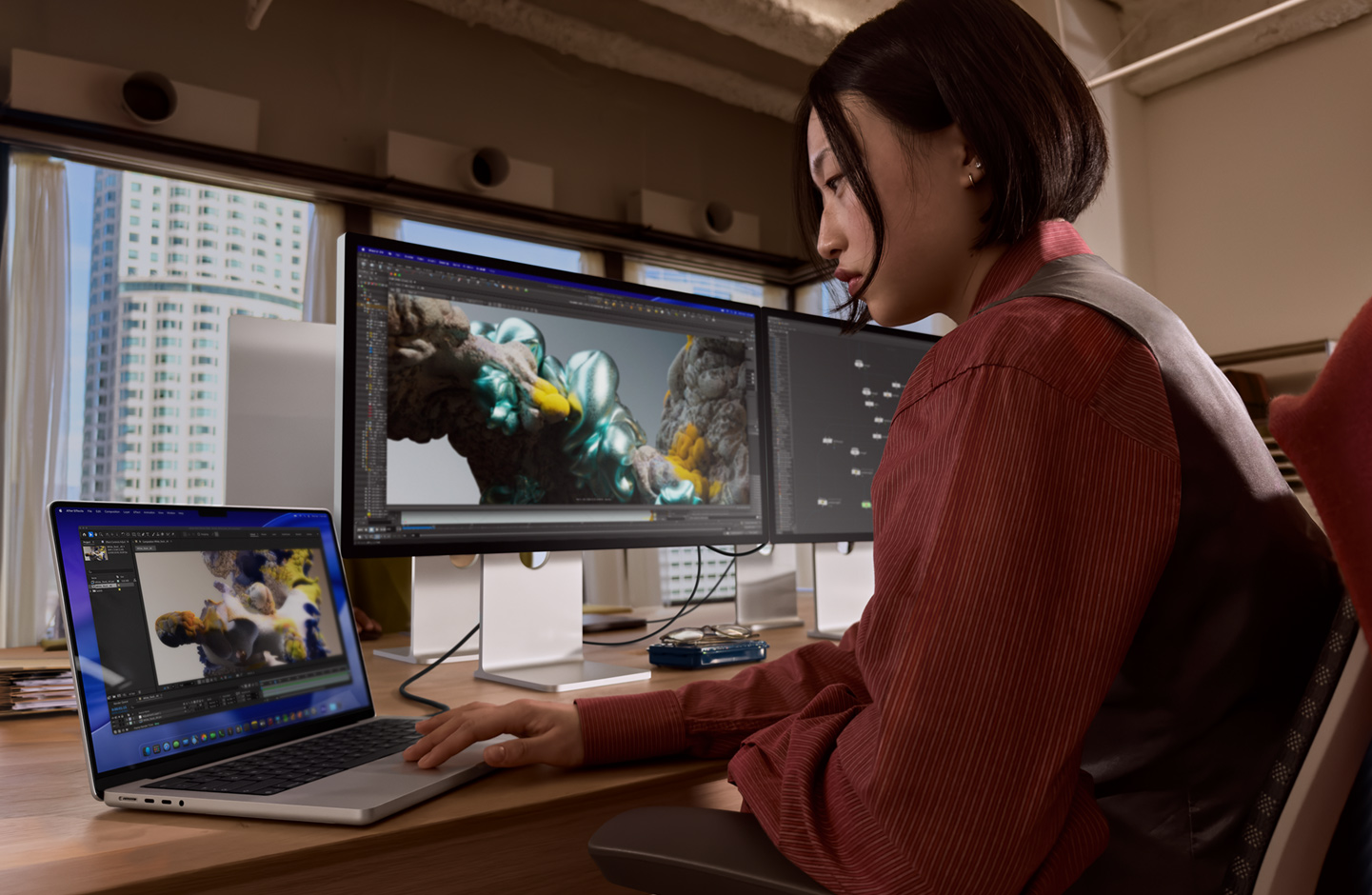 Egy ember irodai környezetben MacBook laptopon dolgozik, amelyhez Thunderbolt 5 porton keresztül egy Studio Display XDR van csatlakoztatva