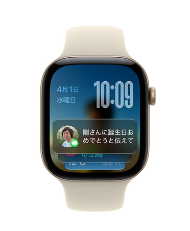 サンドスポーツバンドと組み合わせたライトゴールドアルミニウムケースのApple Watch Series 12。画面の左上に日付、右上に時刻、下部にメッセージのウィジェットが表示されている