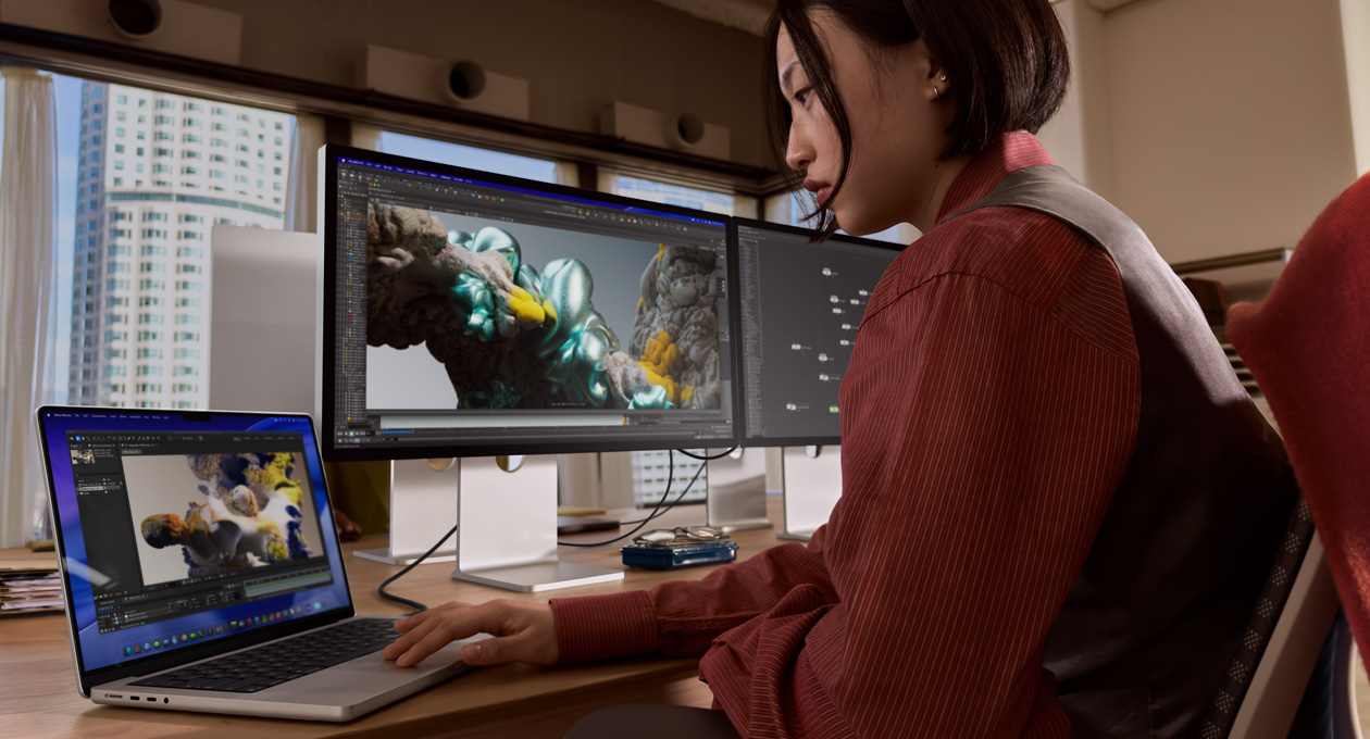 オフィスでMacBookノートブックを使って作業している人物。Thunderbolt 5ポートでStudio Display XDRに接続している