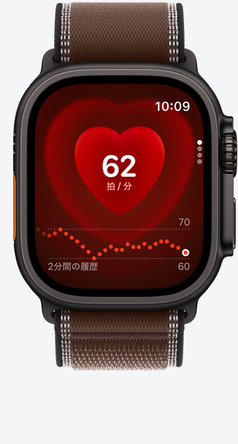 ブラックチタニウムケースのApple Watch Ultra 4。心拍数アプリに現在の1分あたりの心拍数が表示されている。ダークアンバー（ブラウン）のトレイルループバンドが取りつけられている