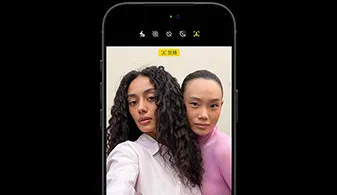 黑色 iPhone 18 Pro 正面圖，畫面中有兩個人物，展示 Center Stage 前置相機的臉部追蹤功能