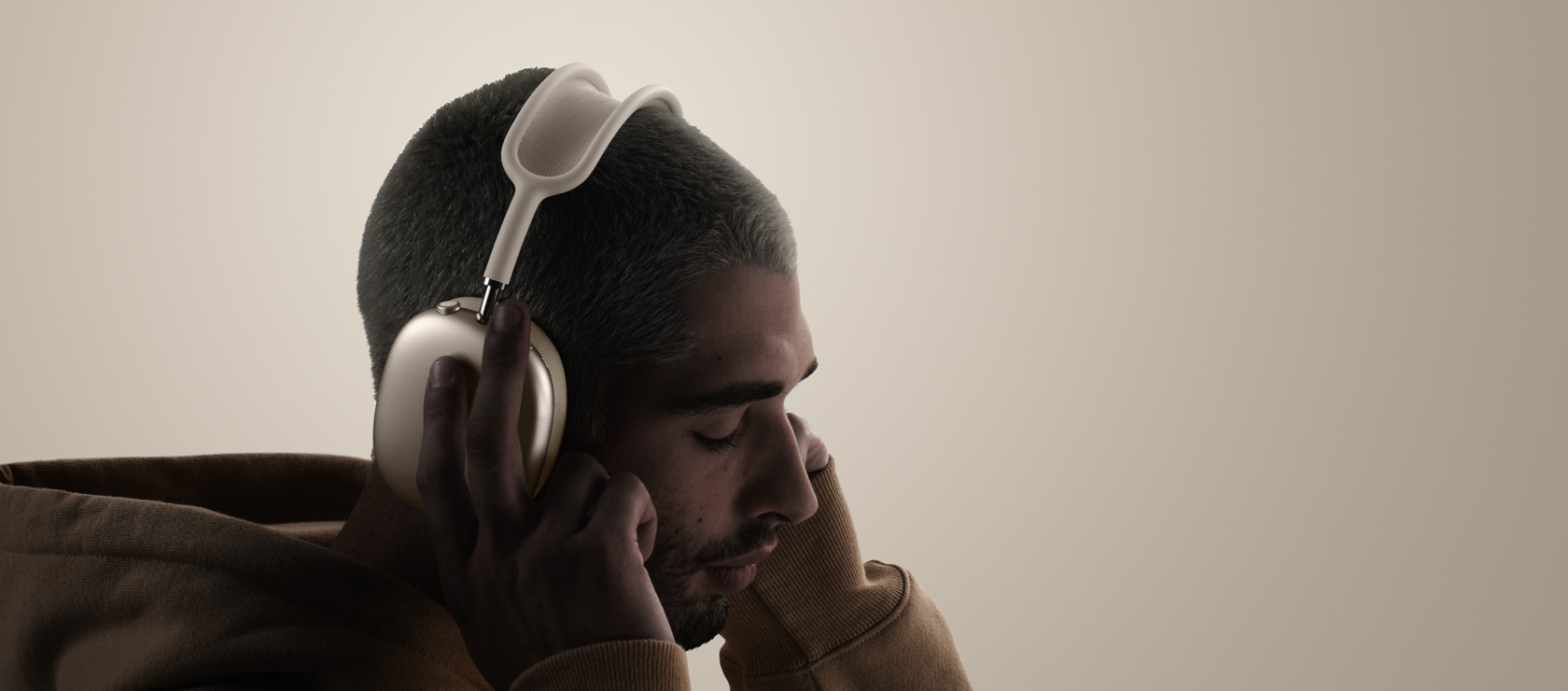 شخص يضع على رأسه سماعات الرأس AirPods Max 2، الجهة الخارجية الجانبية، يلمس بطانة الأذنين