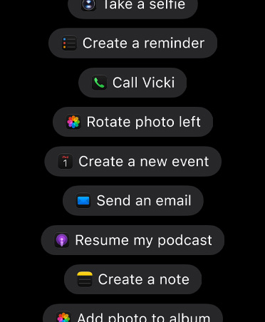 Layar dengan permintaan untuk Siri&nbsp;AI termasuk, Ambil selfie, Buat pengingat, Telepon Vicki, Putar foto ke kiri, Buat acara baru, Kirim email, Lanjutkan podcast saya, Buat catatan, Tambahkan foto ke album