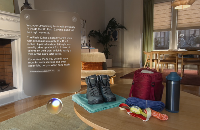Apple Vision Pro view, a conversation with Siri about hiking boots fitting in a backpack hovers above Siri and to the left of a pair of hiking boots and other outdoor gear