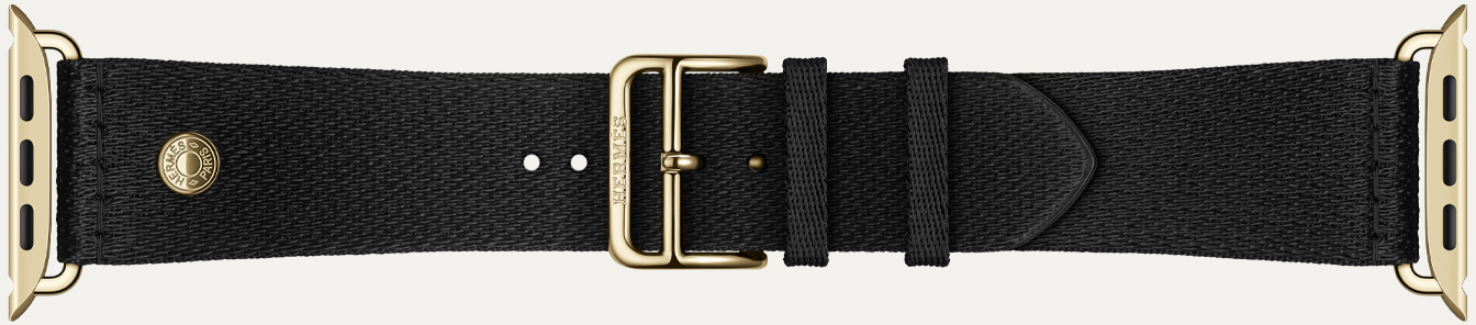 Apple Watch Hermès Series 12 누아 새틴 Clou de Selle 밴드의 디테일. 래디언트 골드 하드웨어가 달린 매끄러운 블랙 새틴 웨빙 소재를 보여주는 모습