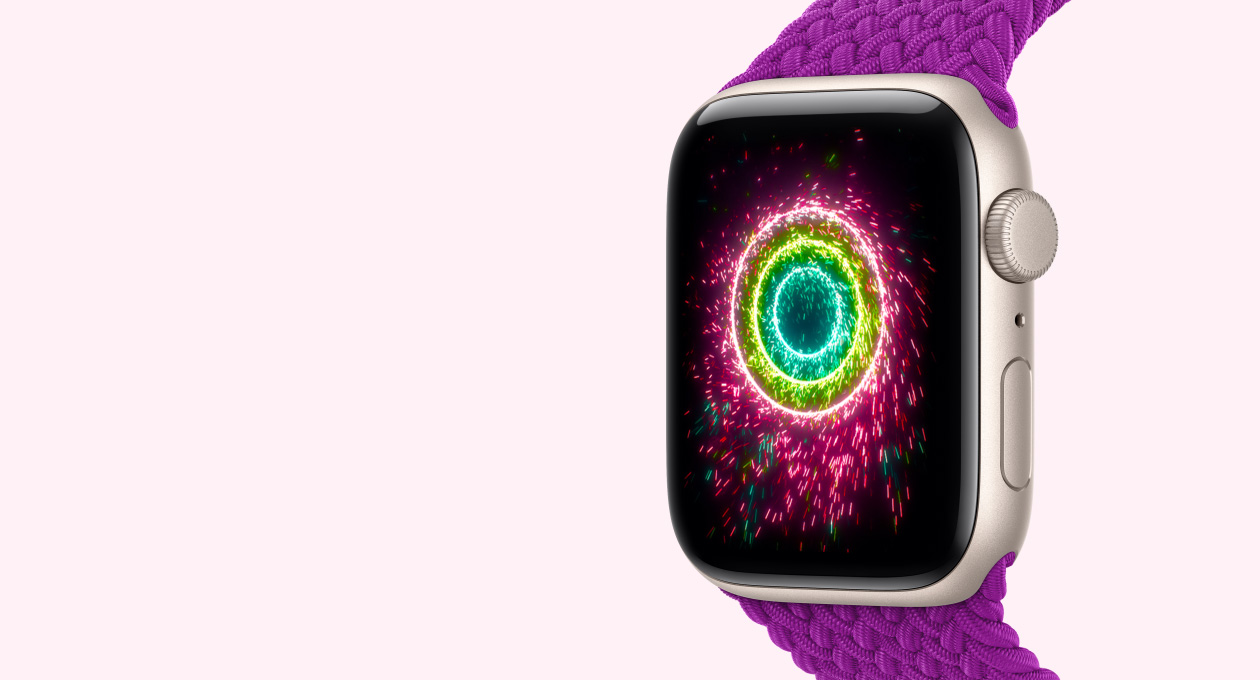 Apple Watch SE 3 com caixa estelar de alumínio e pulseira loop solo trançada magenta, Digital Crown, microfone e botão lateral no lado direito, tela mostrando os círculos de Atividade como fogos de artifício