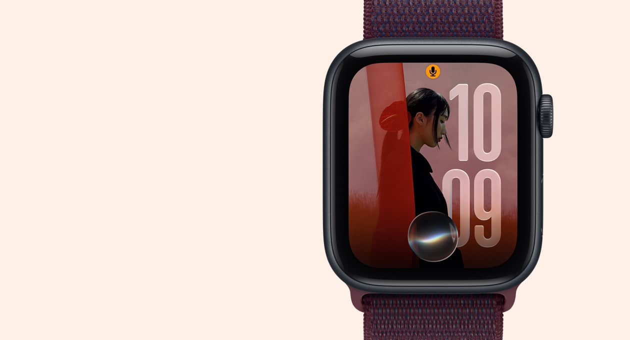 Apple Watch SE 3 com caixa meia-noite de alumínio e pulseira loop esportiva bordô, Digital Crown no lado direito, tela exibindo o mostrador Fotos com o ícone da Siri