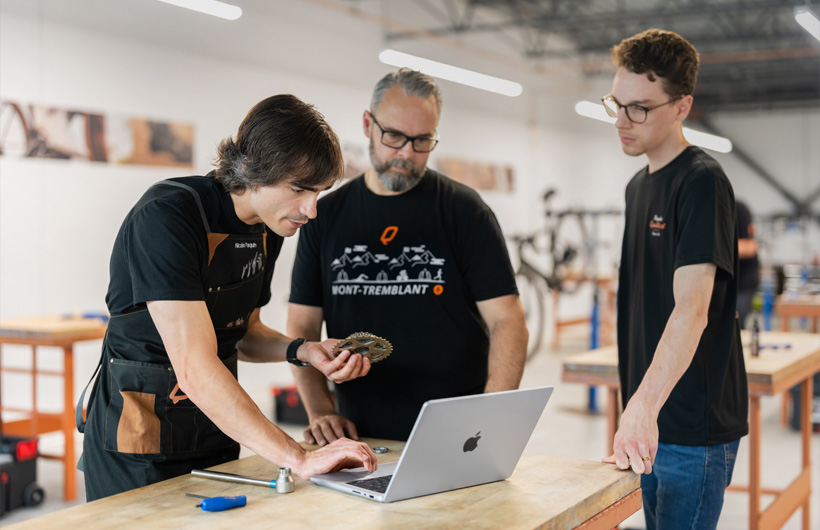 Nicolas Paquin, Ausbilder bei Bicycles Quilicot, nutzt ein MacBook Pro, um auf die Unterlagen für das kostenlose Zertifizierungsprogramm des Unternehmens für Fahrradmechaniker:innen zuzugreifen.