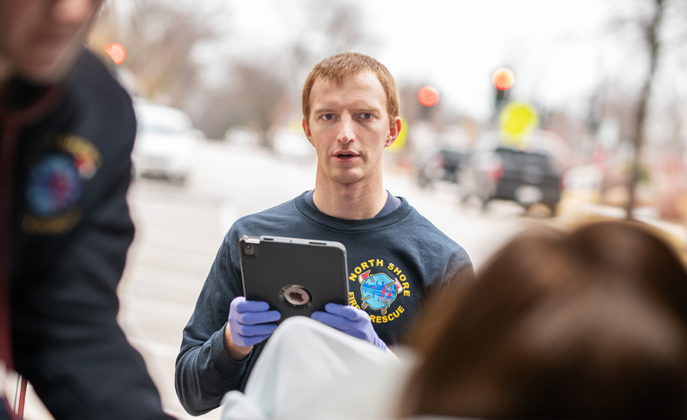En medarbejder med en iPad taler med en patient inde i en ambulance.
