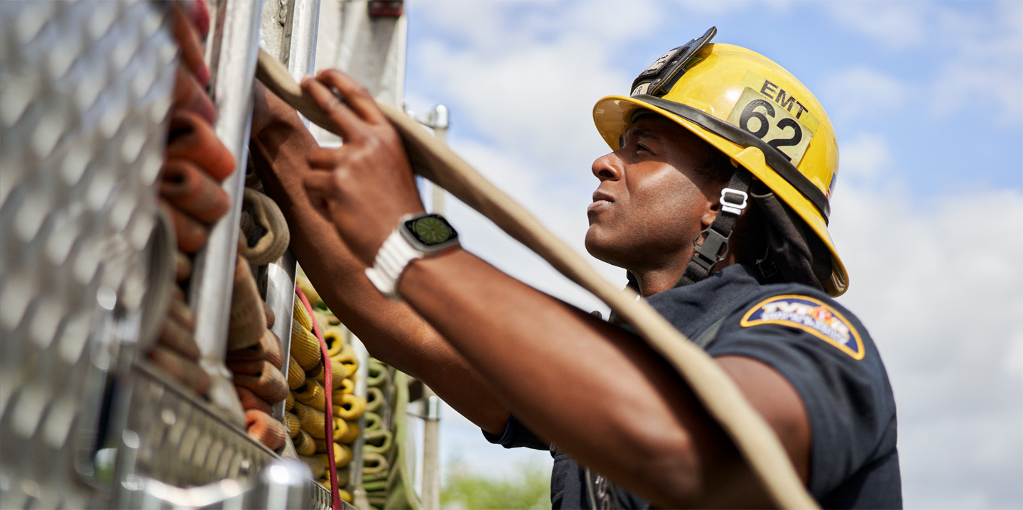 Un bombero que lleva un Apple Watch tira de una manguera en un camión de bomberos