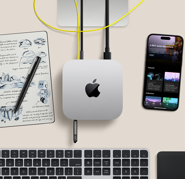 Вид зверху на сріблястий Mac mini, до портів якого підʼєднані кабелі та накопичувач. Поруч на столі бездротова клавіатура, трекпед, iPhone і записник