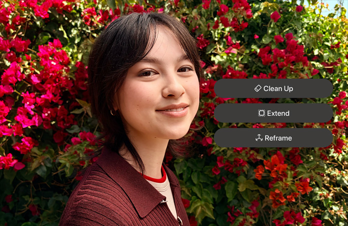 Photo d’une personne souriante aux cheveux bruns, portant un pull marron, entourée de fleurs rouges, démo de retouche photo par IA avec les options Correction, Étendre et Recadrer affichées sur la photo