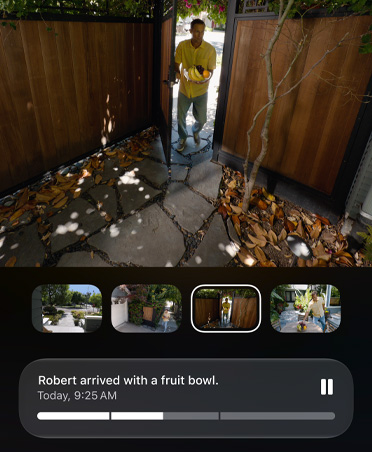 Billeder fra en optagelse med HomeKit-videokamera af en person, der kommer ind i en indhegnet have, AI-genereret beskrivelse på skærmen: Robert er ankommet med en frugtskål, I dag, kl. 09.25
